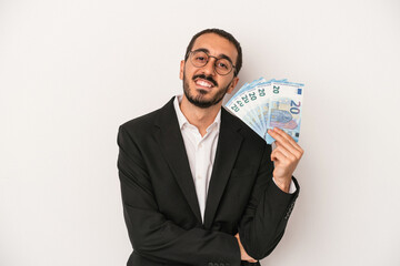 Young caucasian business man holding banknotes isolated on white background laughing and having fun.