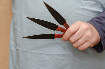 A hand with three knives. Adult male holding throwing knives