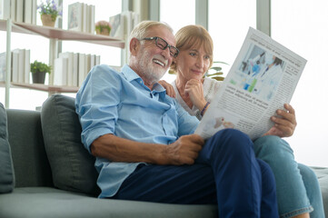 Happy Couple Caucasian senior are relaxing , reading newspaper in living room