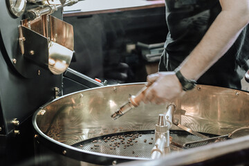 Man pouring coffee beans into the roaster machine. Dark and aromatic coffee beans