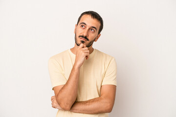 Young caucasian man isolated on white background thinking and looking up, being reflective, contemplating, having a fantasy.