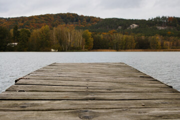 Wooden pier on a lake with autumn forest and rocks in the background, Bohemian paradise, Czech Republic