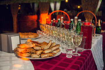 Russian feast. A table set with Russian snacks: pancakes Bliny with stuffing, drinks poured into glasses