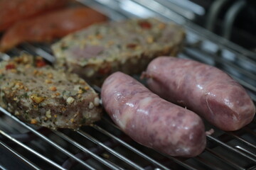 Churrasqueira elétrica com carnes sobre grelha, linguiça, frango e pernil de porco
