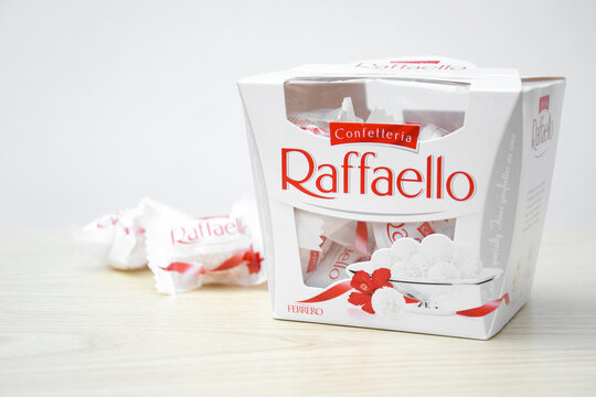 Raffaello sweets on a light wooden table and white background.