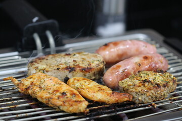 Churrasqueira elétrica com carnes sobre grelha, linguiça, frango e pernil de porco