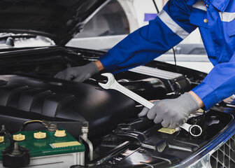 Mechanic works on the engine of the car in the garage.Concept of car inspection service and car repair service.