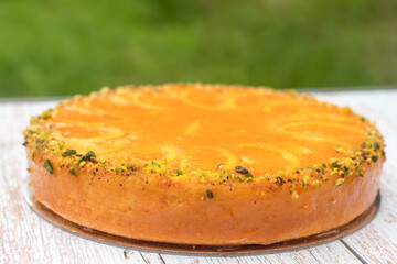 Delicious sweet orange cake decorated with orange slices, orange jam and pistachio nuts on the table. Celebration