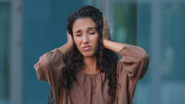 Displeased tired hispanic woman sad girl rolling eyes unhappy face feels disgust from gossip blah blah gesture loud sound conflict covers ears with hands palms refusing to listen hearing rumor ignore