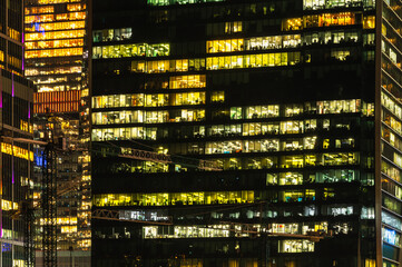 Fototapeta na wymiar Skyscraper windows glow at night. Modern office buildings at night.