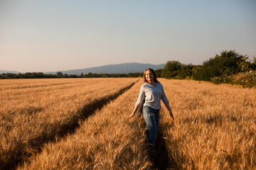 Charming woman enjoying moment, walking in grain field