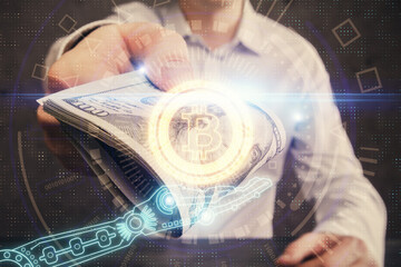 Multi exposure of blockchain theme drawing hologram and USA dollars bills and man hands. Business concept.