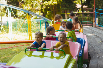 The happy kids on a roller coaster in the amusement park
