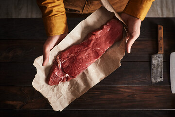 A man holding a piece of meat on paper