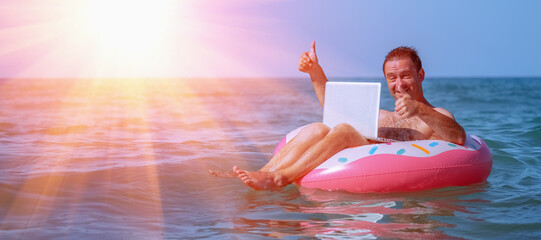 Work from anywhere and remote occupation concept. Portrait of happy businessman freelancer working with laptop computer on inflatable ring in Tropical sea. Copy space.