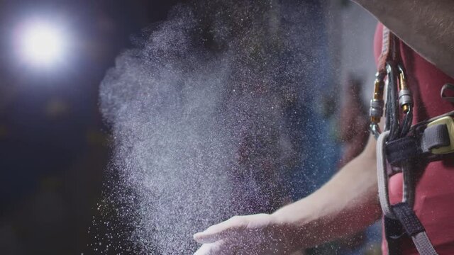 Sports athletic woman uses magnesium for hands, close-up. Dust flies from talcum powder, white chalk powder. Climbing solo in indoor gym. Hobby in the city, healthy lifestyle. Slow motion