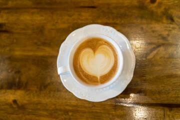 Top view of Latte coffee or cappuccino coffee in white cup with beautiful tree latte art on wooden table.