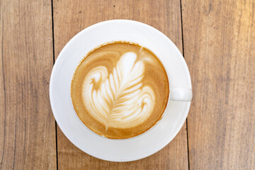 Top view of Latte coffee or cappuccino coffee in white cup with beautiful tree latte art on wooden table.