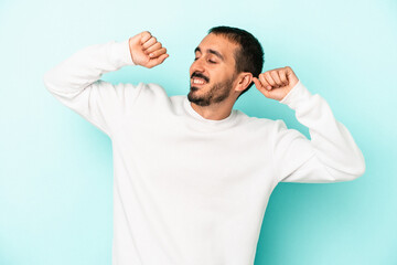 Young caucasian man isolated on blue background celebrating a special day, jumps and raise arms with energy.