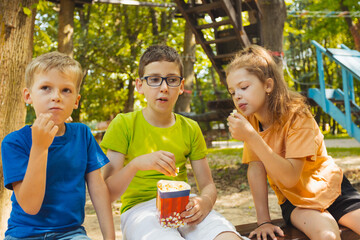 The kids are eating popcorn together in the park