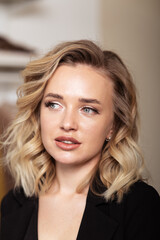 Fototapeta premium Portrait of young lovely blonde woman with curled hair and make-up for filming. Professional styling, curls and makeup.