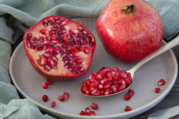 pomegranate on plate, seeds on spoon