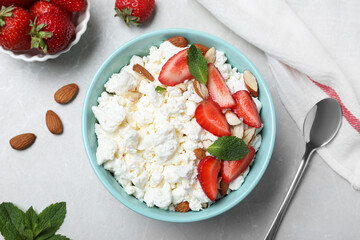 Fresh cottage cheese with strawberry and almond in bowl on light marble table, flat lay