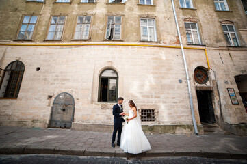 Beautiful young bride with wedding bouquet and groom near old castle before wedding ceremony