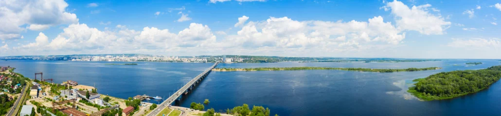 Deurstickers a panoramic view of the banks of the Volga River near Saratov, an automobile bridge across the river in the city limits © miklyxa
