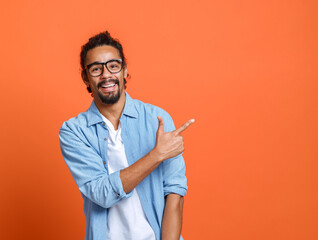 Young happy african american man in glasses pointing with forefinger at copy space