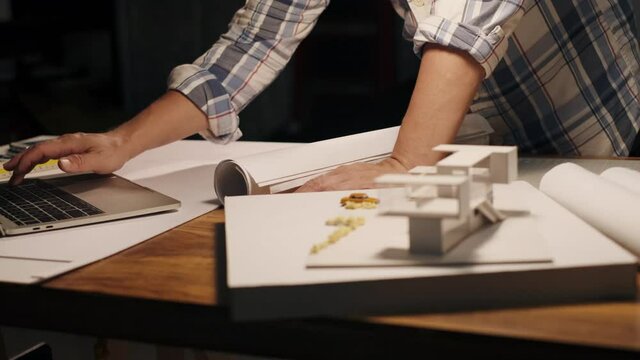 Selective focus. Architect or Engineer professional use computer laptop and blueprint drawing working design making house modelling at his workplace. Architect open drawing blueprint on the desk.
