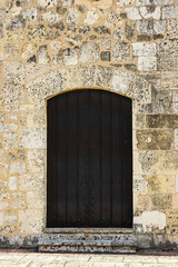 Fototapeta na wymiar ancient stone wall and closed dark door on the facade.