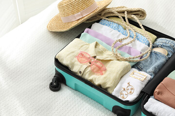 Open suitcase packed for trip and accessories on bed