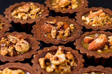 Delicious chocolate tartalets with caramel cream and nuts