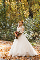 Fototapeta na wymiar blonde girl in a wedding dress in the autumn forest
