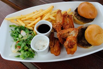 Dinner platter consisting of burger sliders, chicken wings, fish and chips goujons, seasoned fries, BBQ sauce and tartar sauce in Salisbury, UK