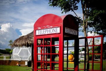 Red phone booth in the park and blurred background.