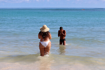 Interracial couple on a beach, white overweight woman and her black boyfriend in sea water - obrazy, fototapety, plakaty