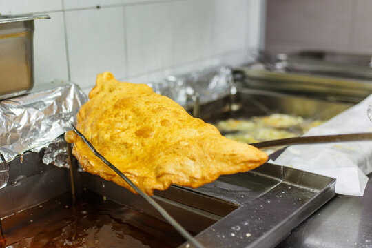 Pizza fritta napoletana ripiena di ricotta e cicoli appena uscita dall'olio bollente