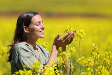 Happy woman touching and smelling flowers in a field