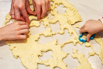 Parents and kids cook sweet cookies in the kitchen together. Family traditions and having fun