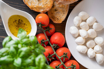 fresh ripe basil leaves with aromatic tomatoes and italian mozzarella, on the table. next to bruschetta and olive oil with Provencal herbs
