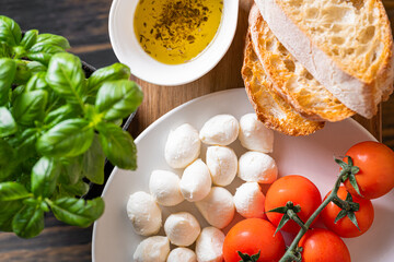 fresh ripe basil leaves with aromatic tomatoes and italian mozzarella, on the table. next to bruschetta and olive oil with Provencal herbs