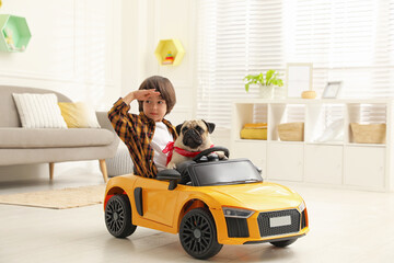 Little boy with his dog in toy car at home
