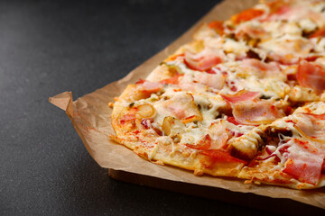 pizza with bacon, vegetables and sauce on dark concrete table