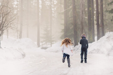 Fototapeta na wymiar Fun Boy and Girl Running in the Snow Trees Fog Beauty Nature Health Fresh Air