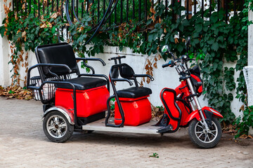 Red electric rickshaw or e-rickshaw commercial vehicle display with selective focus under daylight at kemer, turkey. Rent transport for tourists.