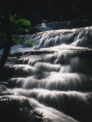 Scenic view of Erawan Waterfall. Breathtaking smooth flowing white water stream closeup with sunlight in lush rainforest. Kanchanaburi, Thailand. Minimal long exposure.