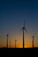 viele Windräder bei Sonnenuntergang stehen auf einem Feld und produzieren Strom	