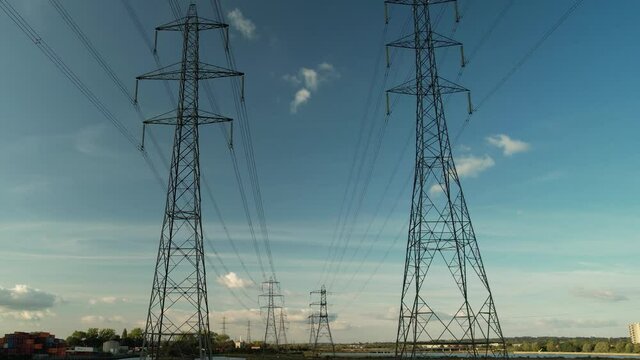 Electricity Pylons Against Blue Sky At Eling Great Marsh, Southampton, England, UK - drone shot